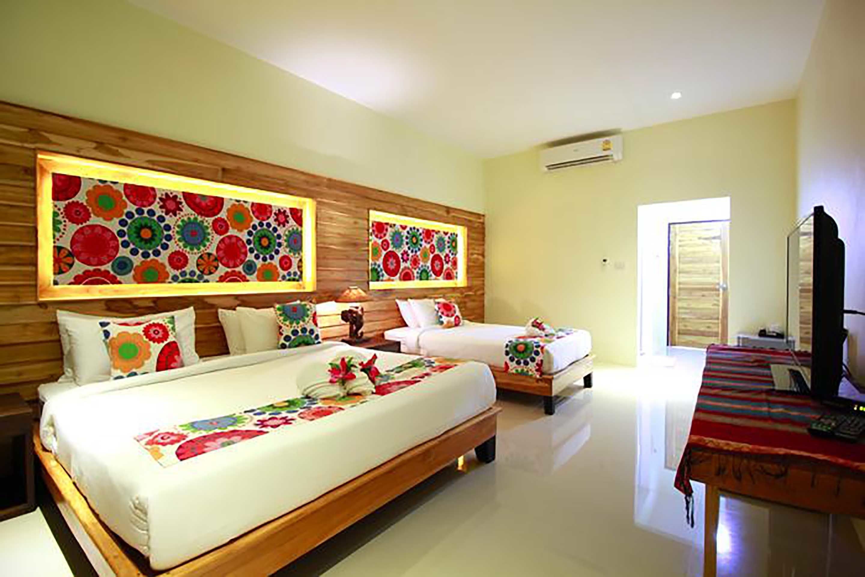 A hotel room with two beds, a desk with a computer, and decorative wall art.