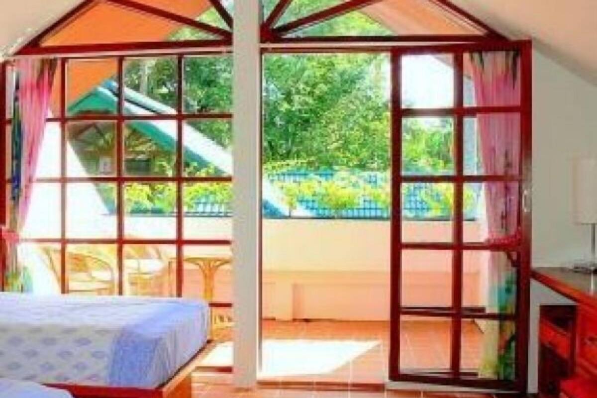 Une chambre à coucher avec un lit, un bureau et une fenêtre donnant sur un jardin.