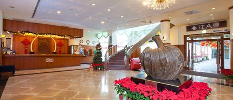 Un hall amplio con una recepción, una gran escultura decorativa y una escalera que sube a otro nivel.