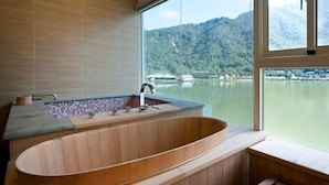 A modern bathroom with a freestanding bathtub, a large window offering a view of a lake and mountains. - Lakeside Resort Hotel (Puli)
