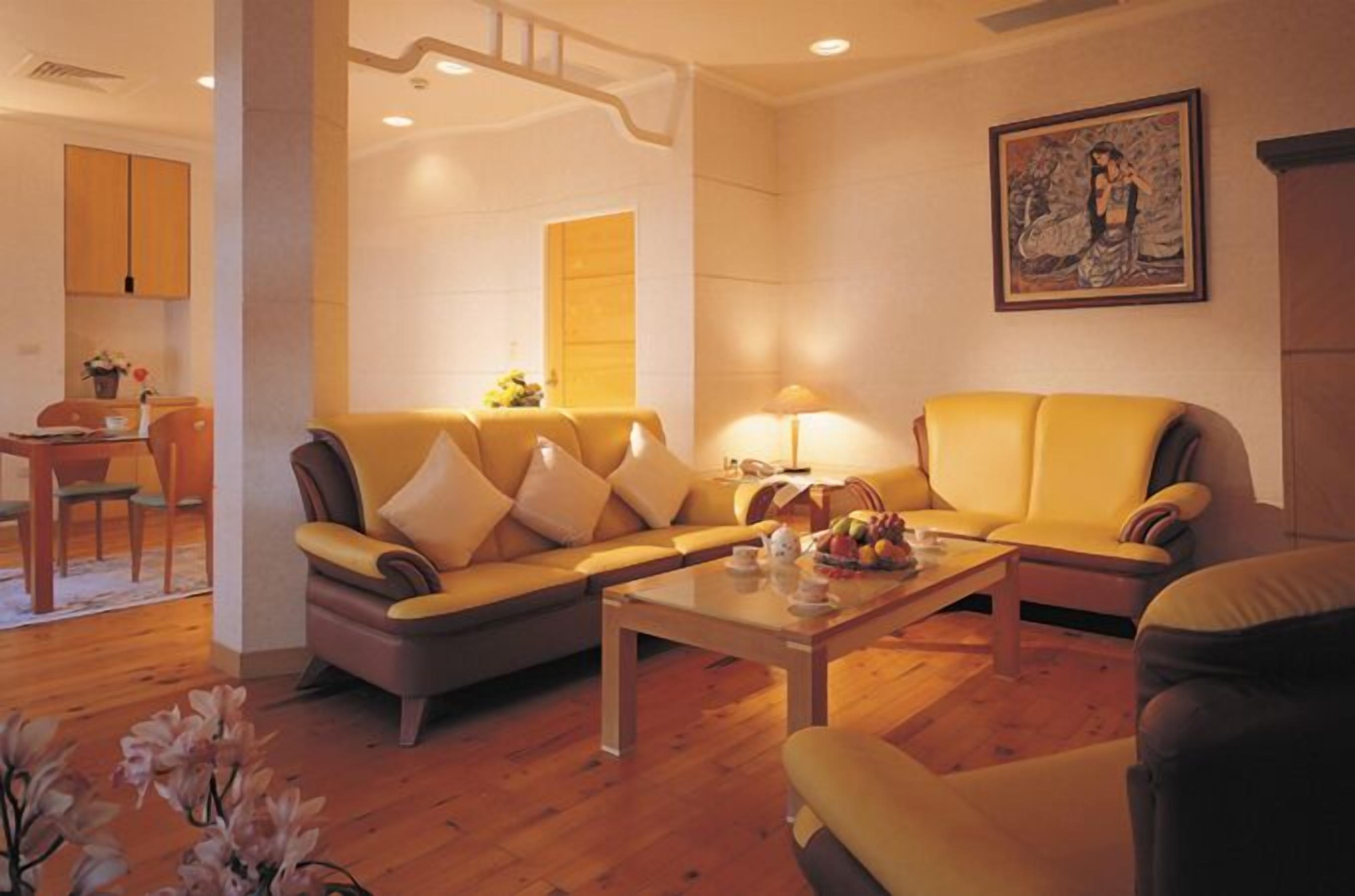 Una sala de estar con un sofá, sillones, una mesa de centro y un cuadro en la pared.