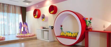A children's play area with a slide, a circular seating area with toys, and a small table with a lamp.
