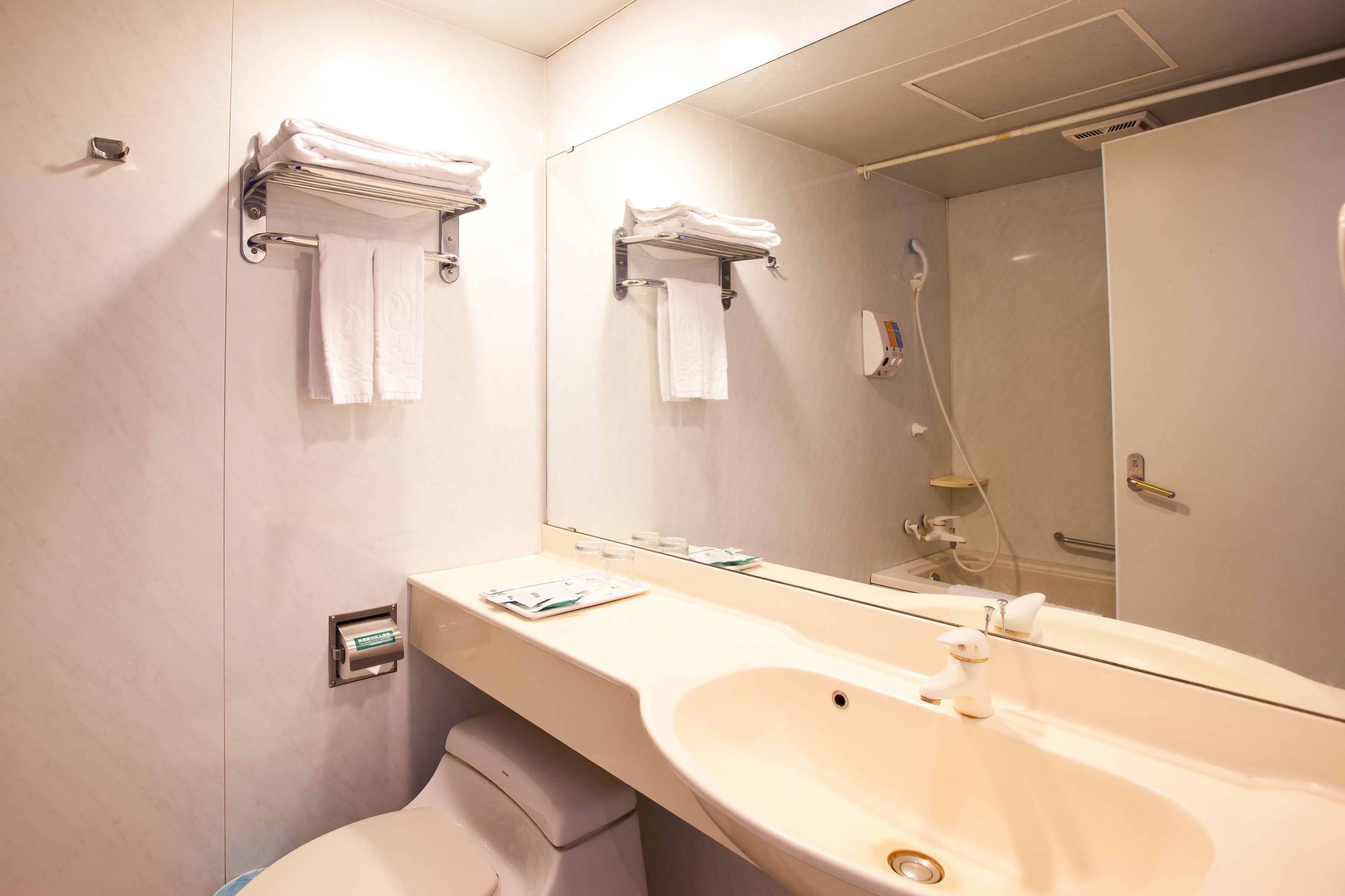 Un baño moderno con un lavamanos grande, un espejo y dos toalleros.