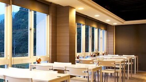 A dining area with multiple tables and chairs, large windows, and a wooden floor. - Lakeside Resort Hotel (Puli)