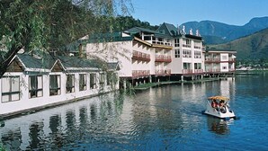 A building with multiple balconies overlooking a calm lake, surrounded by trees and mountains in the background. - Lakeside Resort Hotel (Puli)