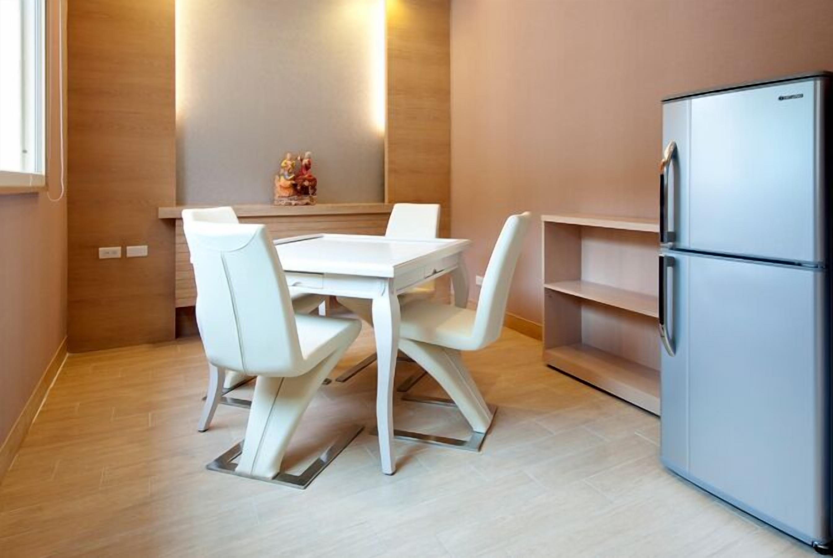 A modern kitchen with a white table and chairs, a stainless steel refrigerator, and a wooden cabinet.