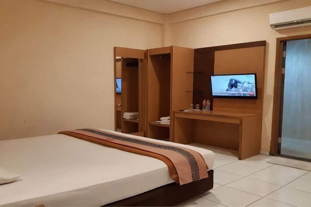 A hotel room with a bed, a TV, a desk, and a wardrobe.