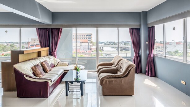 A modern living room with a sofa, armchair, and a coffee table. - Ayothaya Riverside Hotel Ayutthaya (Ayutthaya)