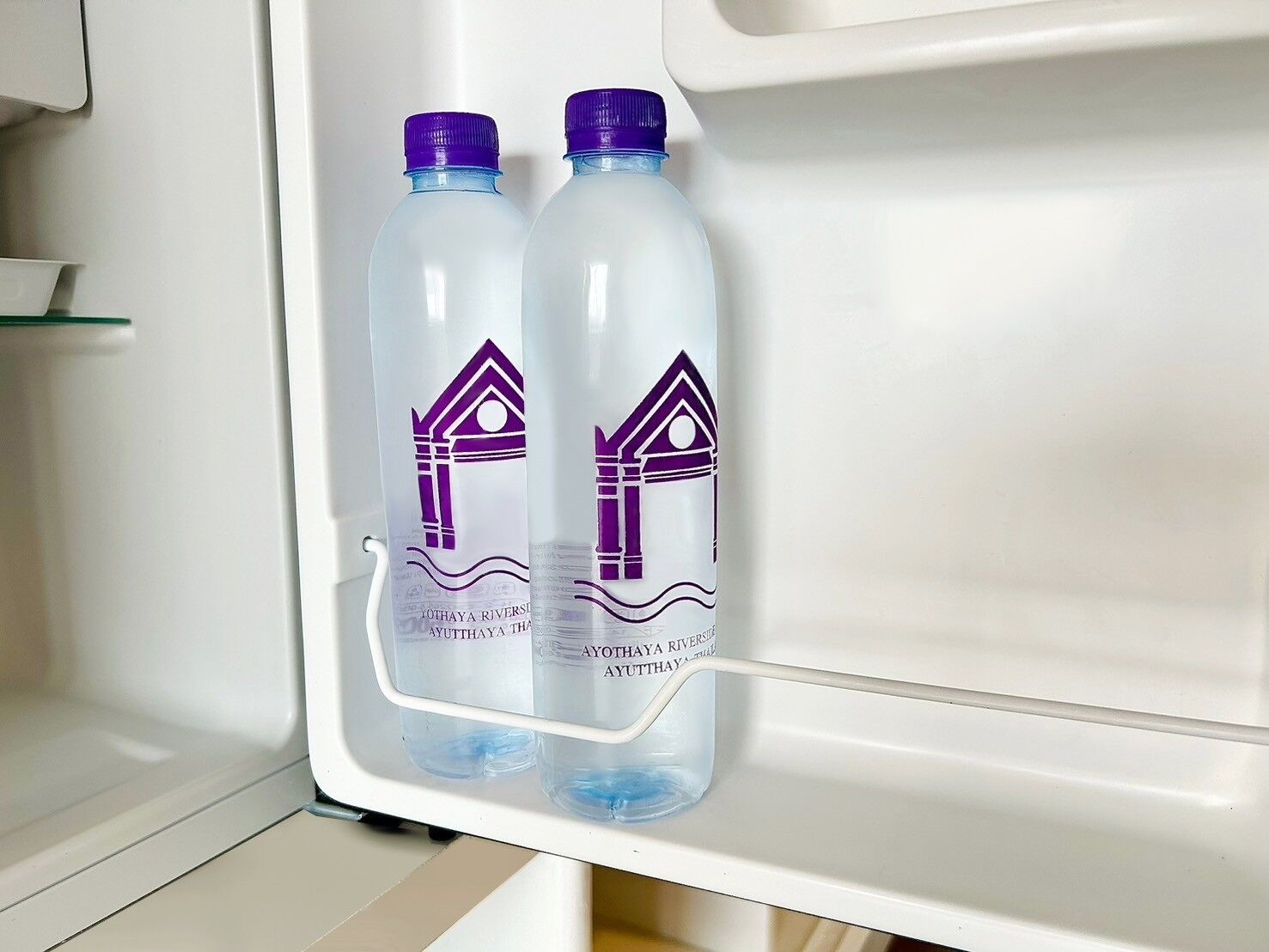 Een koelkast met twee waterflessen op de deurplank.