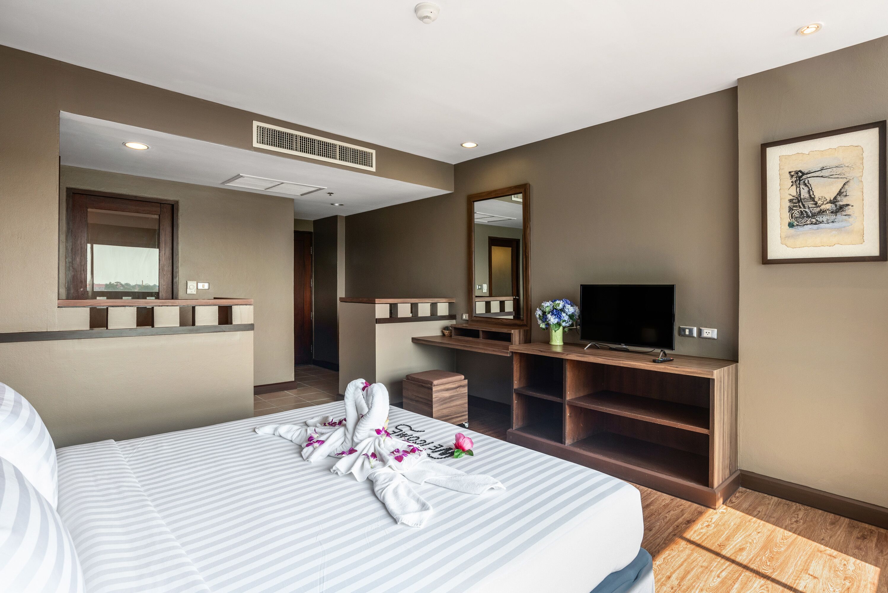 A hotel room with a bed, a TV, a desk, and a mirror.