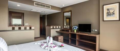 A hotel room with a bed, a TV, a desk, and a mirror.