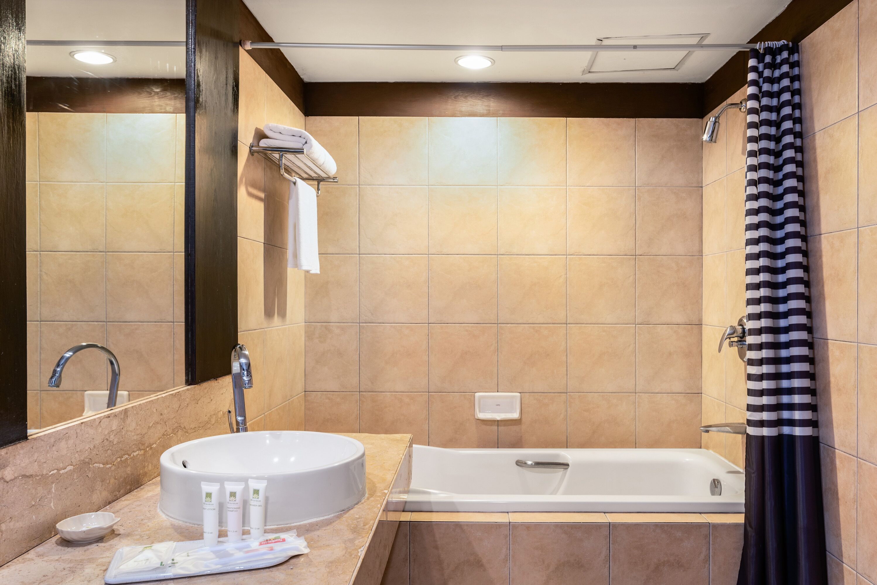 Een badkamer met een rond wastafel, een badkuip en een douchegordijn.