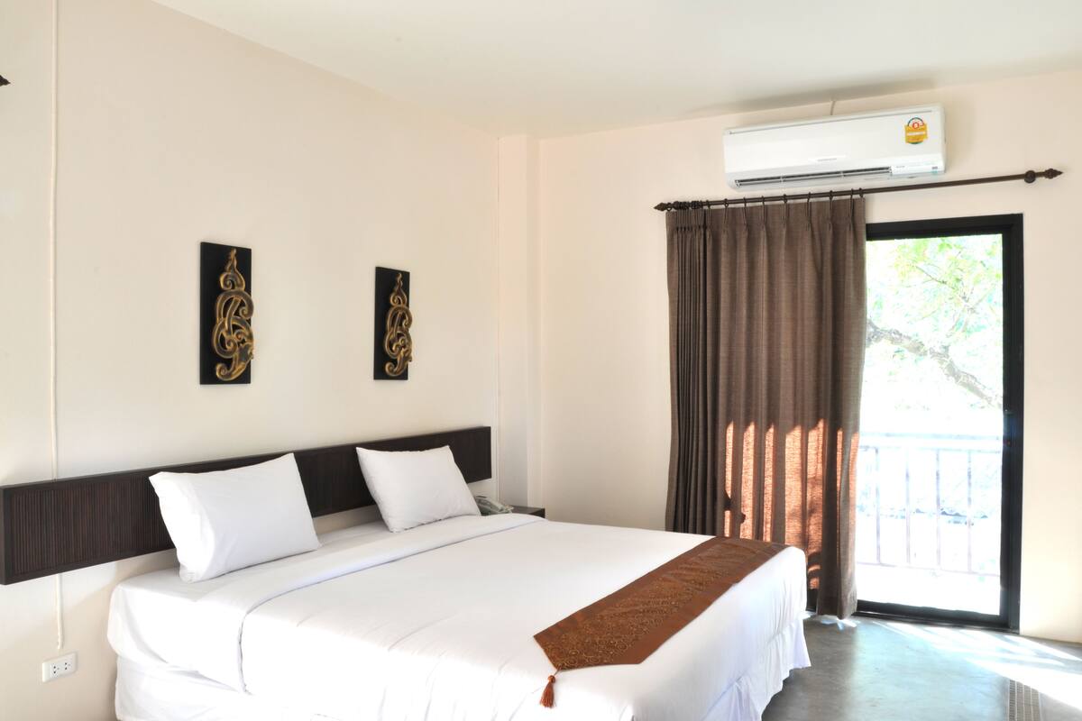 Une chambre d’hôtel avec un grand lit, un ventilateur de plafond et une vue sur l’extérieur grâce à une porte vitrée.
