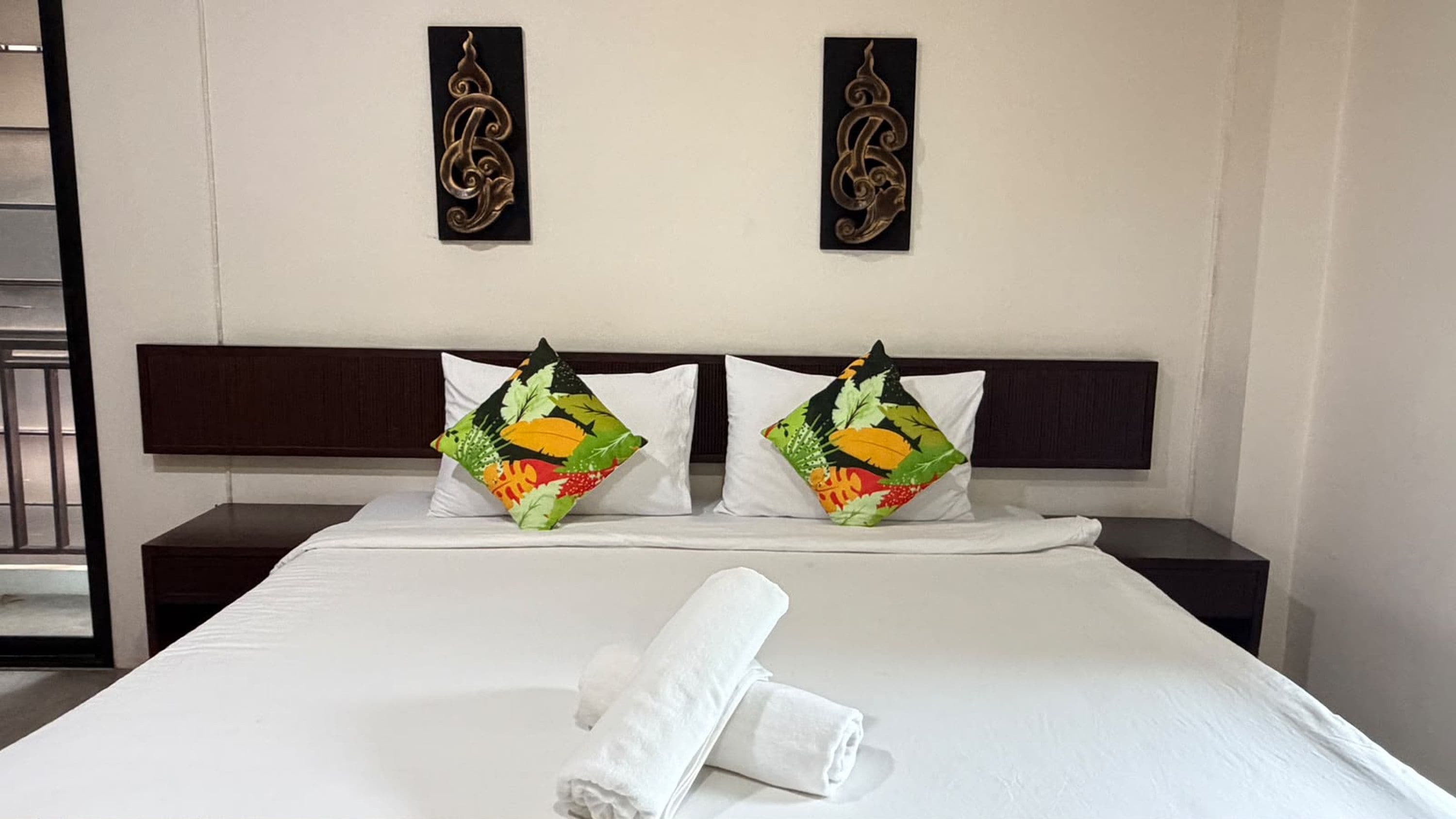 Ein Hotelzimmer mit einem Bett, zwei Wanddekorationen und zwei Kissen mit Obstmotiv.