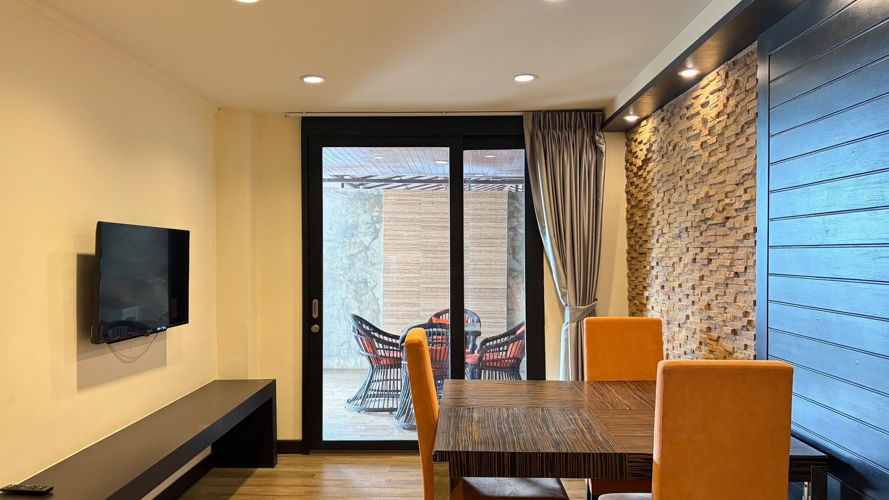 A dining area with a TV mounted on the wall, a bench, and a table with chairs.
