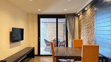 A dining area with a TV mounted on the wall, a bench, and a table with chairs.