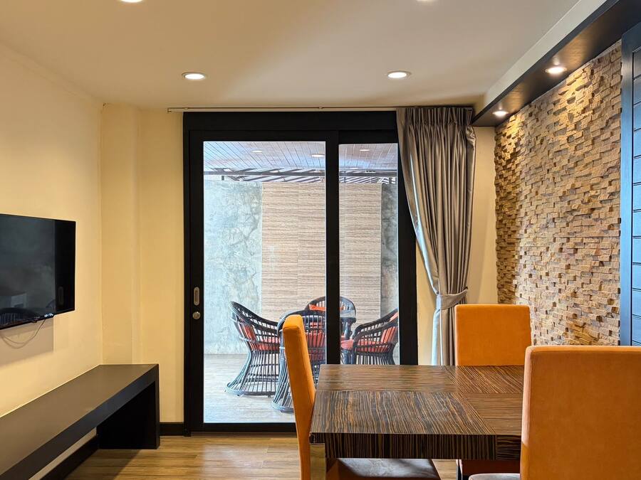 A dining area with a TV mounted on the wall, a bench, and a table with chairs.