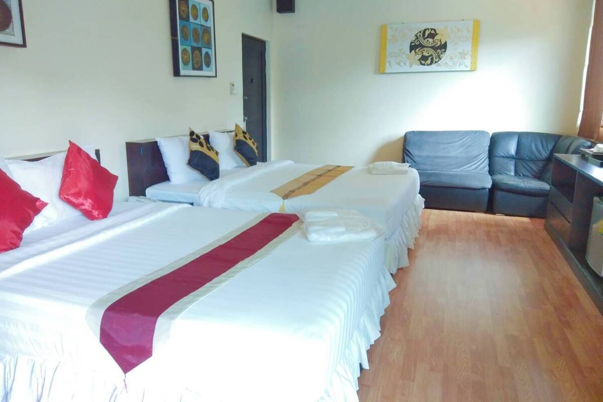 Une chambre d’hôtel avec deux lits, un canapé et un bureau.