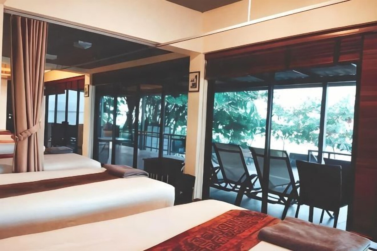 A hotel room with two beds, a view of the outdoors, and a balcony with chairs.