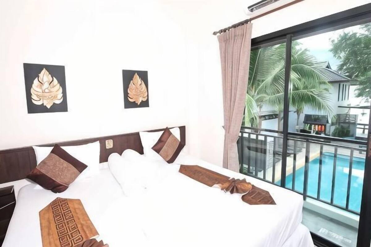 Une chambre d’hôtel avec un grand lit, une vue sur une piscine et deux éléments de décoration encadrés accrochés au mur.