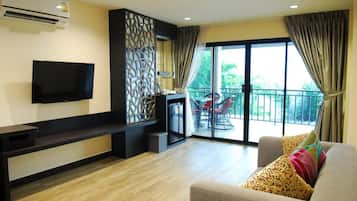 Een moderne woonkamer met een flatscreen televisie, een bank met gestreepte kussens, een decoratief wandpaneel en een balkon met buitenmeubilair.