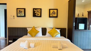 A hotel room with a bed, pillows, a headboard, a wall-mounted phone, and framed artwork.