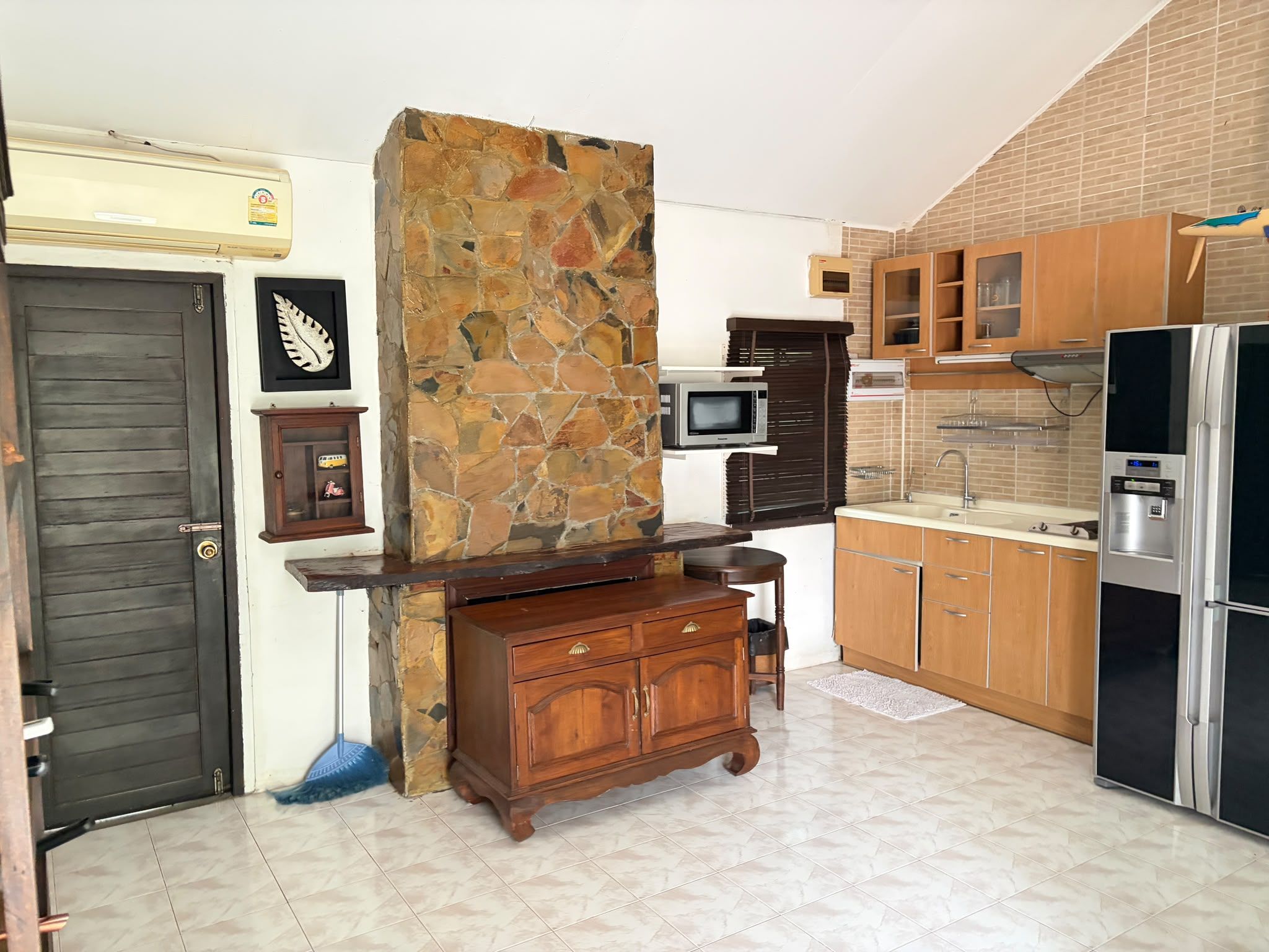 Eine Küche mit einer Steinwand, Holzschränken, einer Mikrowelle und einem Kühlschrank.