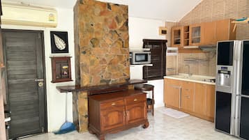 Eine Küche mit einer Steinwand, Holzschränken, einer Mikrowelle und einem Kühlschrank.