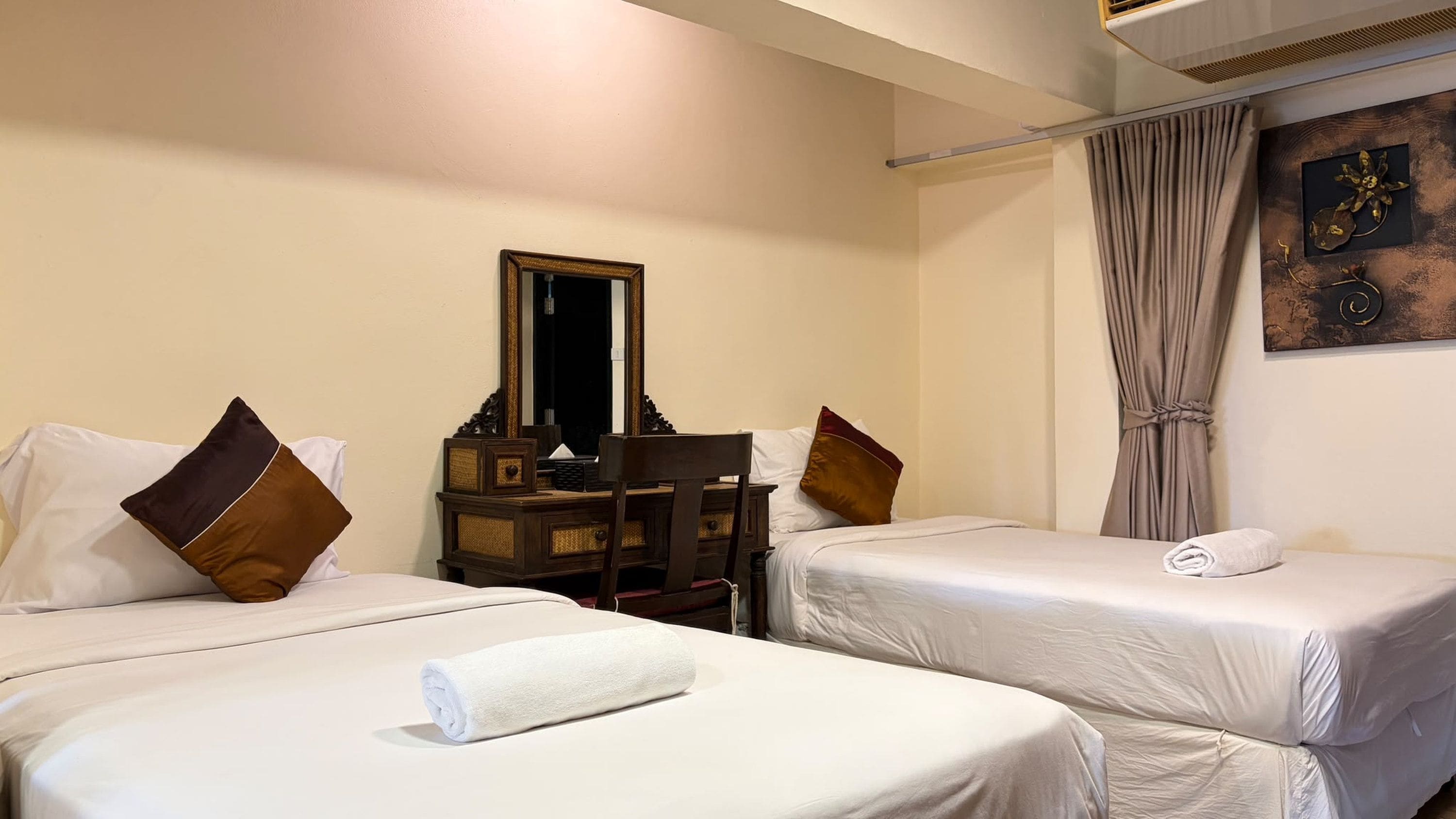 Una habitación de hotel con dos camas, un aparador, un espejo y una cortina.