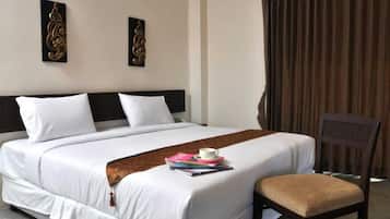 A hotel room with a large bed, a bedside table with a cup and books, and a chair.