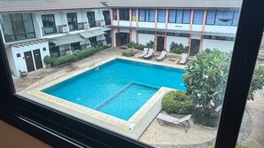 A swimming pool with lounge chairs and a building with multiple floors and balconies.