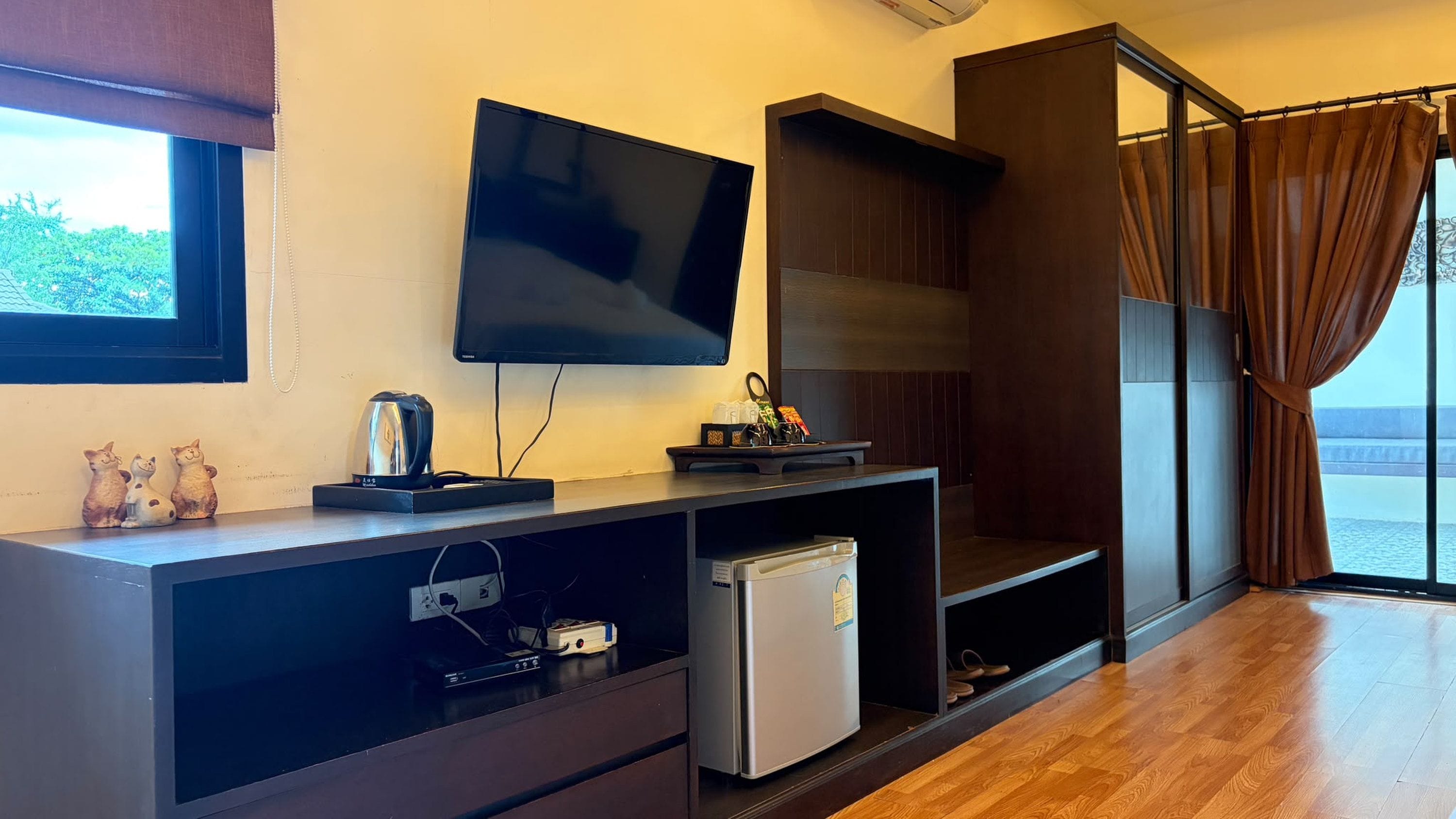 Una sala de estar moderna con un televisor de pantalla plana, un refrigerador pequeño y piso de madera.