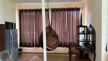 Een woonkamer met een hangstoel, een eettafel, een houten kast en een decoratieve lantaarn.