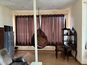 A living room with a hanging chair, a dining table, a wooden cabinet, and a decorative lantern. - Palette Monsane River Kwai Resort (Kanchanaburi)