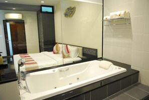 A modern bathroom with a large bathtub, a mirror, and a towel rack. - Monsane River Kwai Resort (Kanchanaburi)