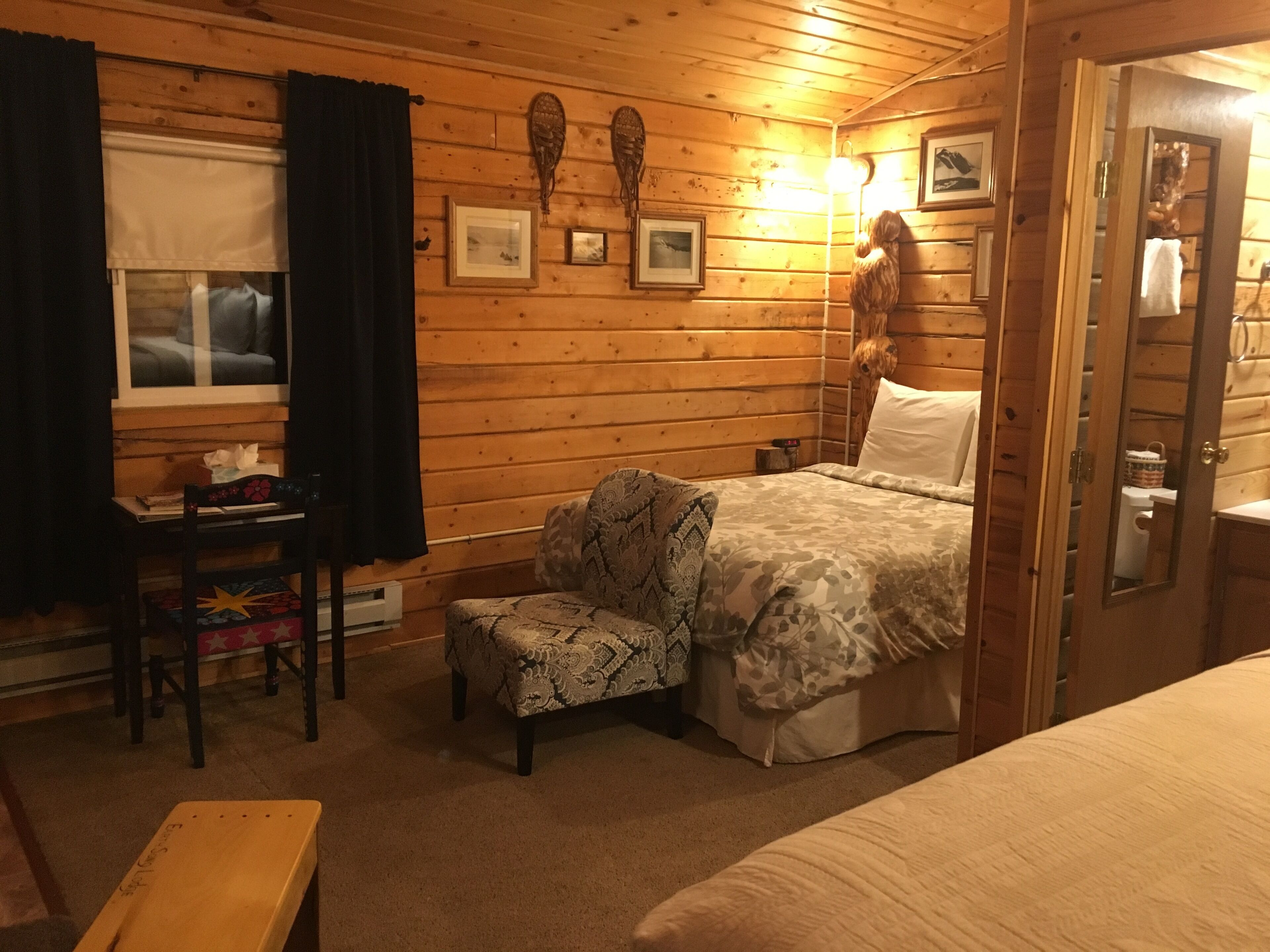 Une pièce confortable avec un lit, une chaise, un bureau et une fenêtre avec des rideaux.