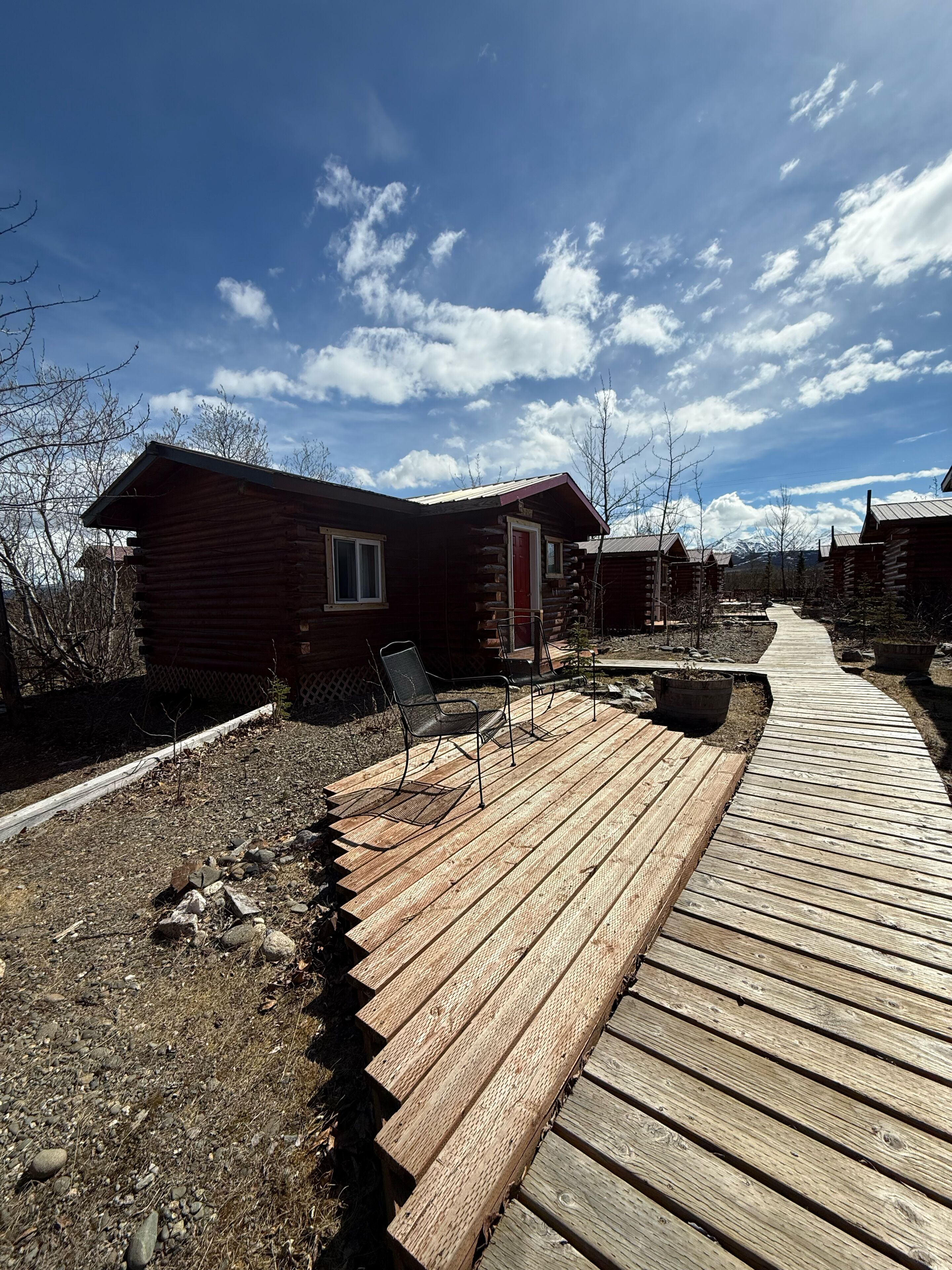 A wooden deck leading to log cabins with a clear sky.