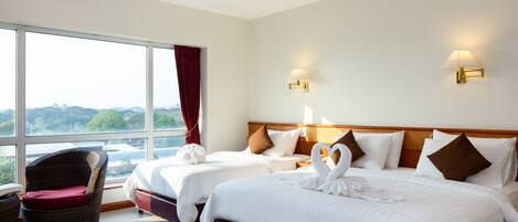 A hotel room with two beds, a large window, a chair, and wall-mounted lamps.