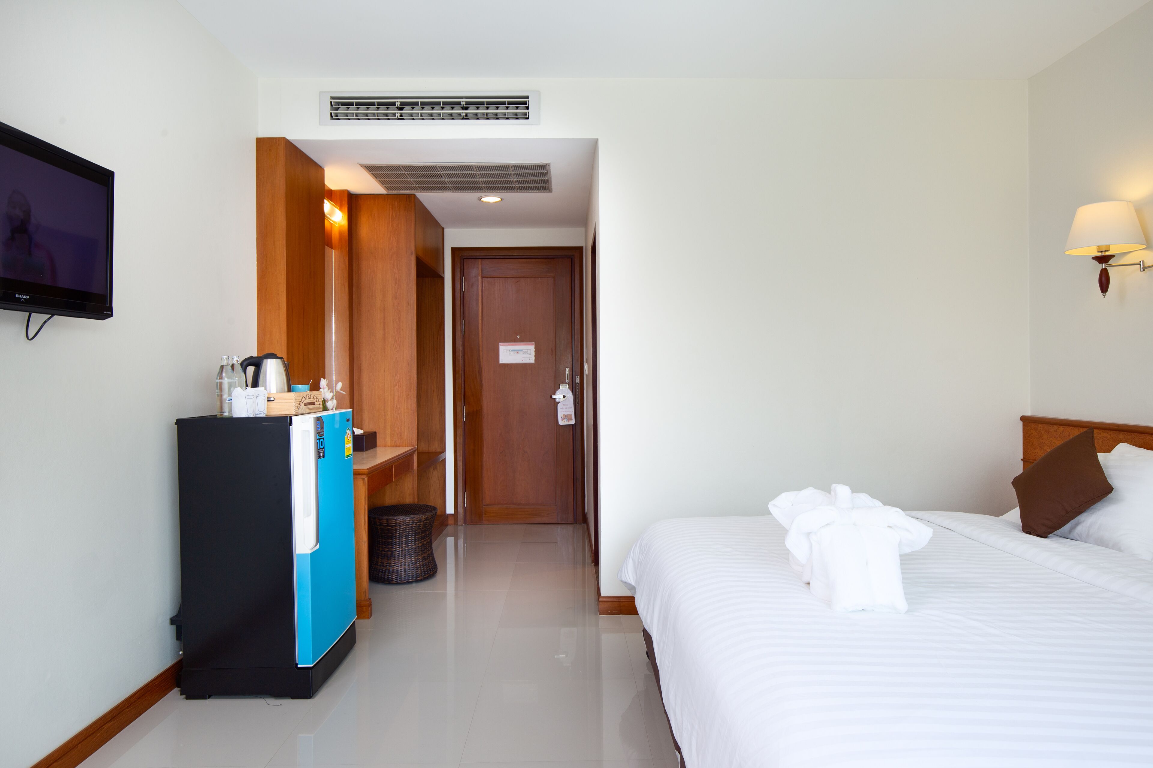 Une chambre d’hôtel équipée d’un lit, d’une télévision, d’un mini-bar et d’une armoire en bois.