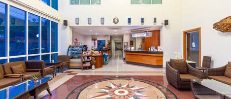 Un vestíbulo de hotel con mostrador de recepción, zona de estar y un gran diseño de brújula en el piso.