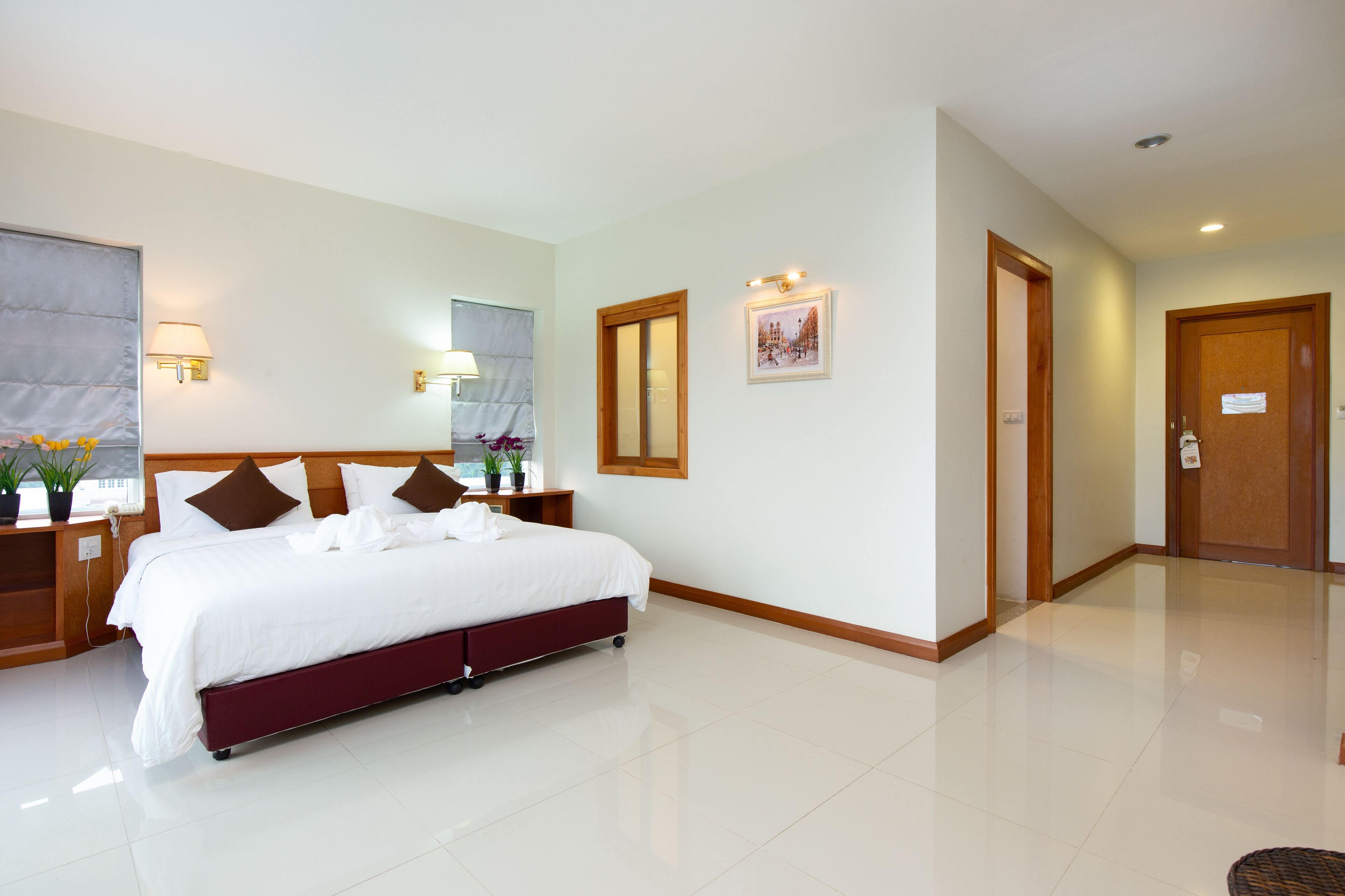 A hotel room with a large bed, bedside tables, a mirror, and a door.