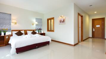 A hotel room with a large bed, bedside tables, a mirror, and a door.