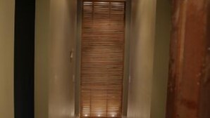 A narrow hallway with wooden flooring and a closed door at the end. - The Harkness Hotel (McCammon)