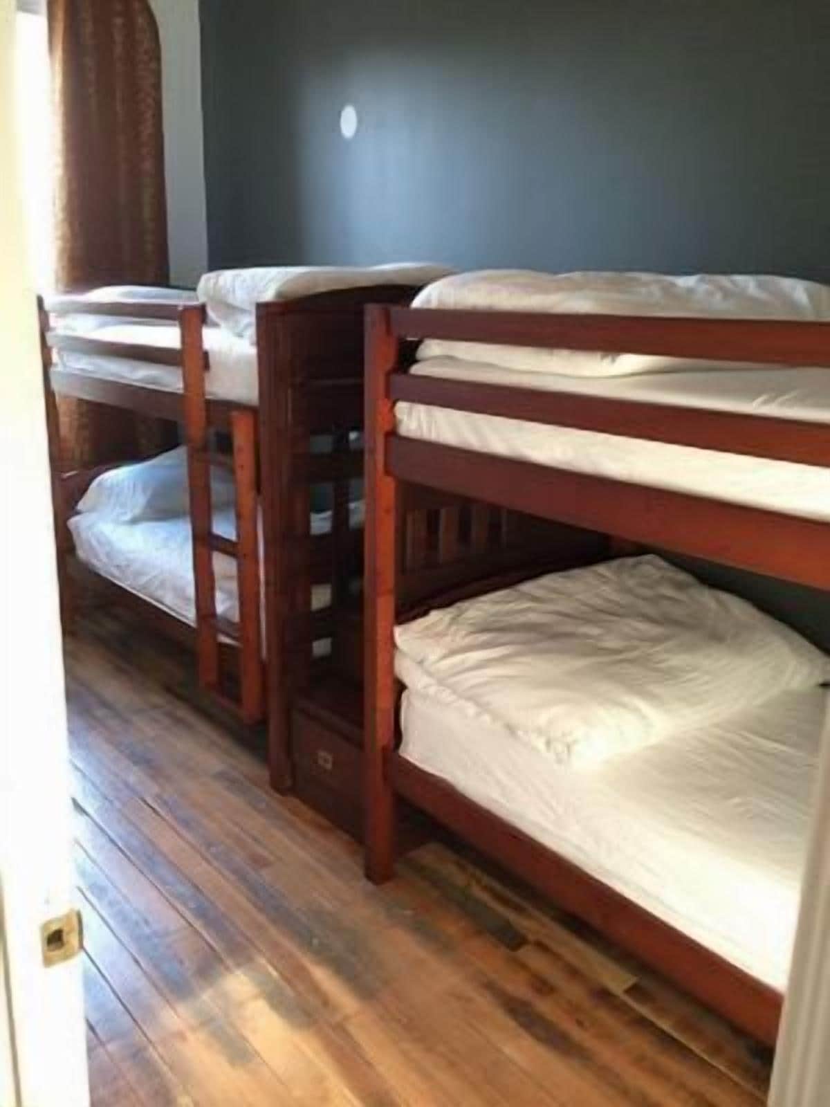 Quarto com beliches e piso de madeira.
