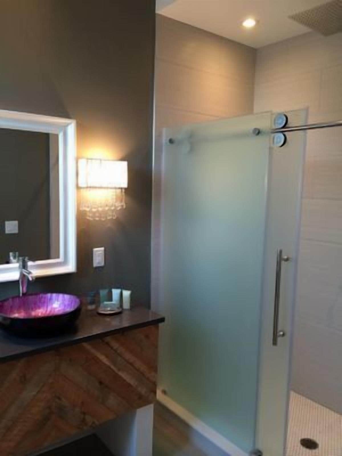 A bathroom with a modern sink, a glass shower enclosure, and a wall-mounted mirror.