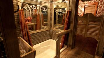 A rustic bathroom with a wooden bathtub, a mirror, and a sign that reads "Barber House."
