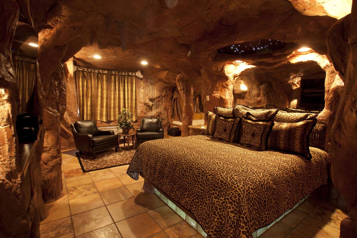 A cave-themed bedroom with a large bed, a chair, and a small table.