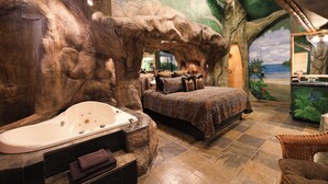 A room with a large bathtub, a bed with a leopard print bedspread, and a mural of a tree and jungle. - Black Swan Inn (Pocatello)