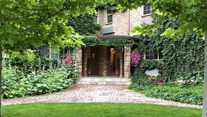 A stone building with a brick entrance, surrounded by lush greenery and flowering plants. - Black Swan Inn (Pocatello)