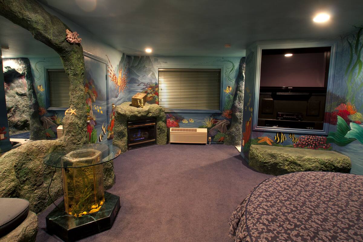 A room with a large aquarium, a fireplace, and a mural of a marine scene.